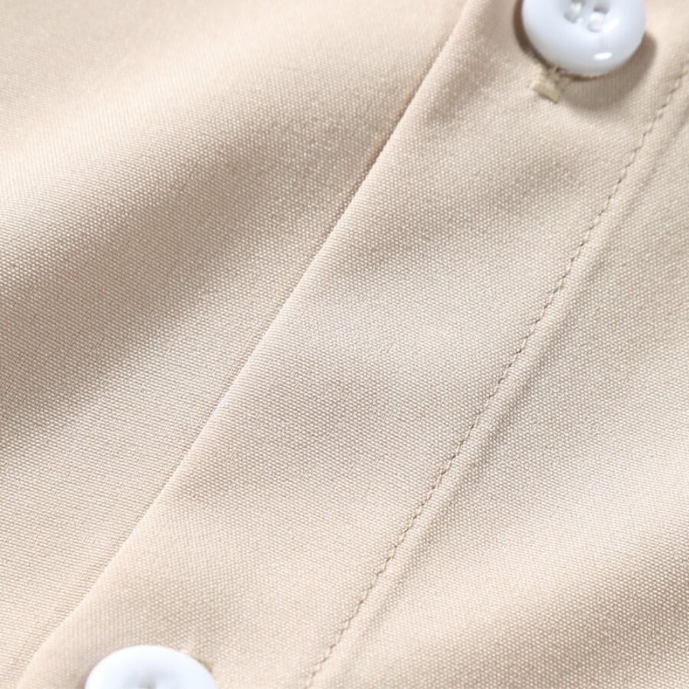 Detalhe do botão da Camisa Vinser Atacama, destacando os botões resistentes, as costuras reforçadas, o acabamento refinado e o tecido leve na cor bege claro, evidenciando a qualidade premium da peça.