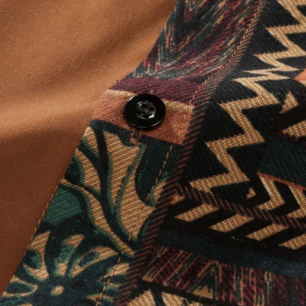 Detalhe da camisa masculina Vinser Atins em tecido marrom com estampa geométrica e botão preto.