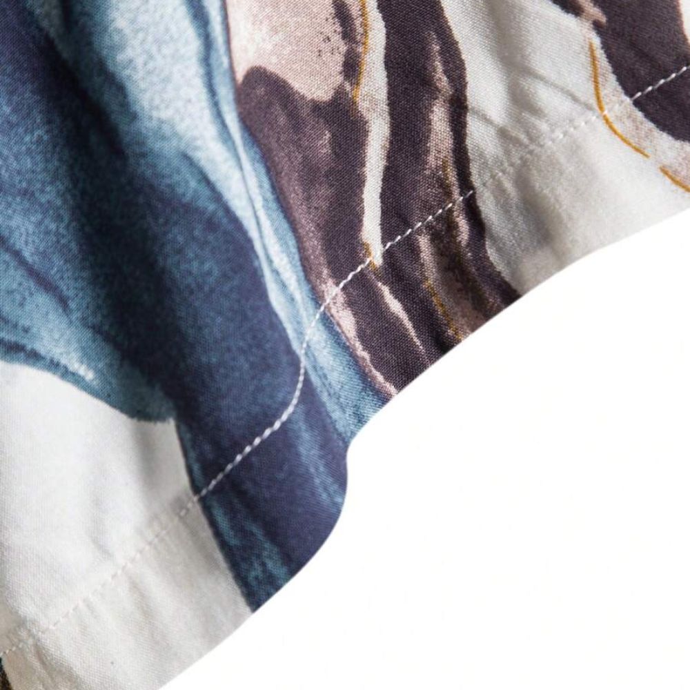 Detalhe da costura da Camisa Vinser Azul Atlântico, destacando o acabamento reforçado e a estampa abstrata em tons de azul, branco, cinza e dourado sobre tecido leve.