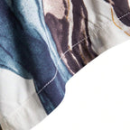 Detalhe da costura da Camisa Vinser Azul Atlântico, destacando o acabamento reforçado e a estampa abstrata em tons de azul, branco, cinza e dourado sobre tecido leve.