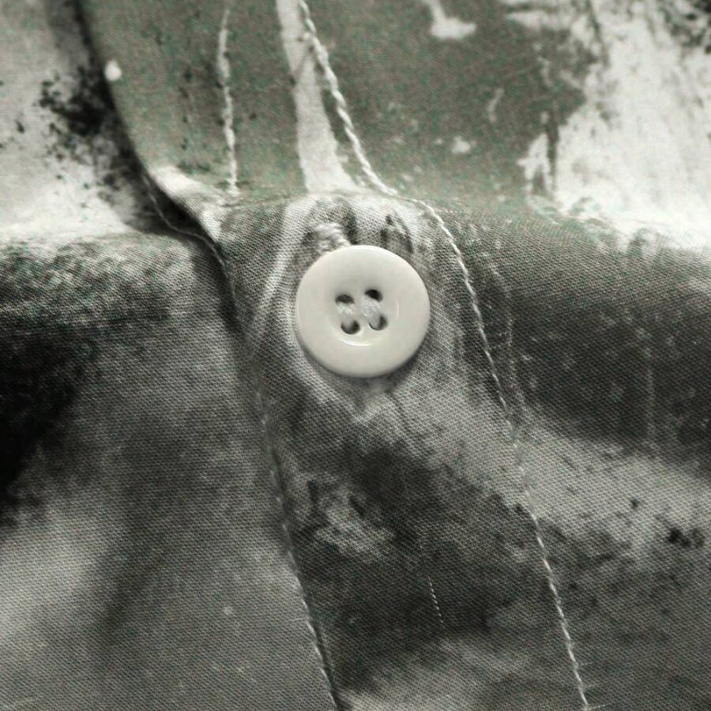 Detalhe do tecido da Camisa Vinser Brisa Costeira, destacando a textura, o botão frontal e a estampa abstrata em tons de preto, cinza e branco.