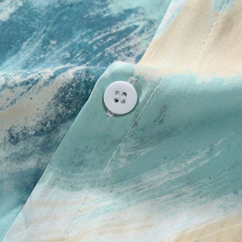 Detalhe da estampa da Camisa Vinser Brisa Marítima, destacando o tecido leve, o botão frontal e o acabamento em tons de azul, verde e bege inspirados no movimento do mar.