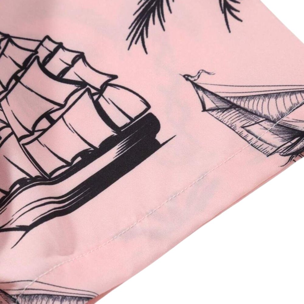 Detalhe da manga da camisa masculina Vinser Campeche Rosa, com estampa tropical de veleiros e paisagens praianas em preto sobre fundo rosa, evidenciando o acabamento da costura e a qualidade do tecido.