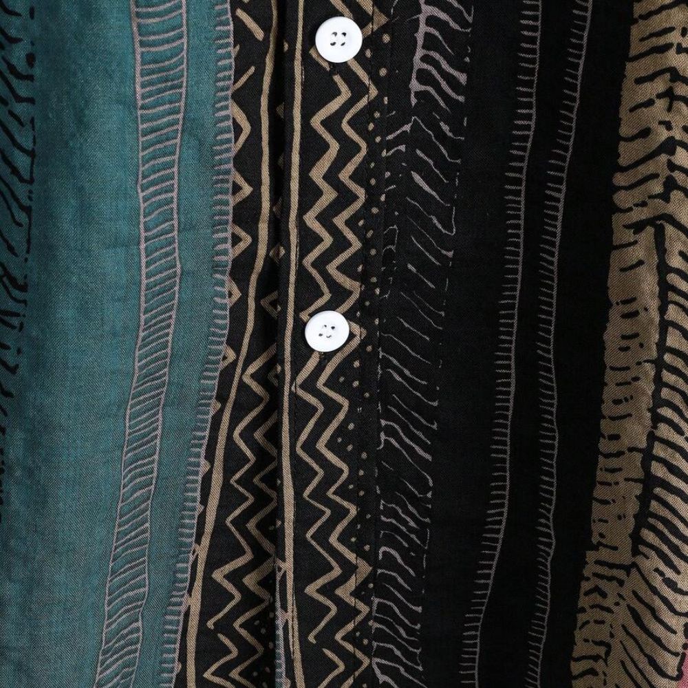 Detalhe do tecido da Camisa Vinser Canion, destacando a estampa listrada em tons de verde-petróleo, preto, bege e marrom, a textura do tecido, as costuras refinadas e o acabamento premium, evidenciando conforto e qualidade.