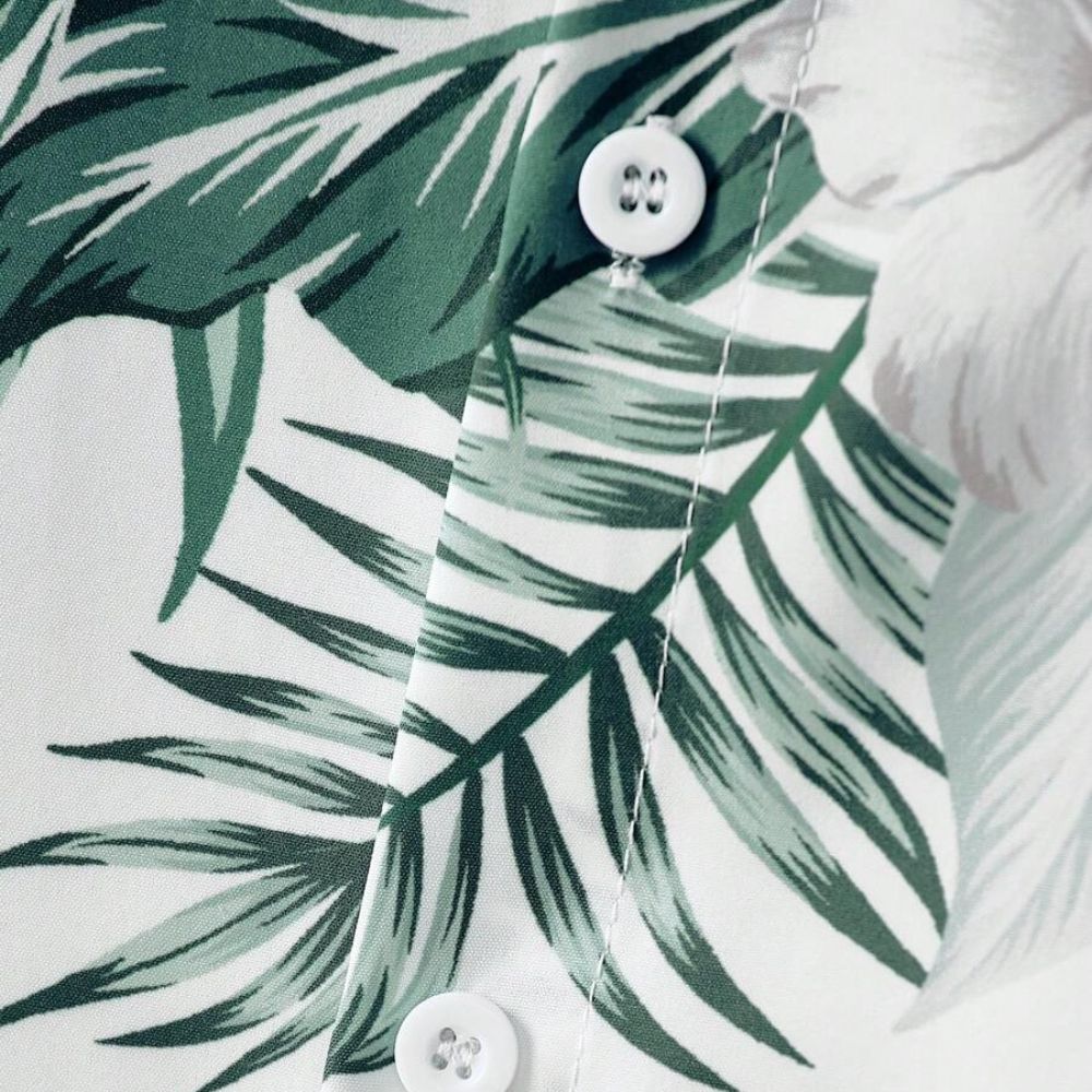 Detalhe da camisa masculina Vinser Comporta branca com estampa de folhagens verdes e botões frontais.