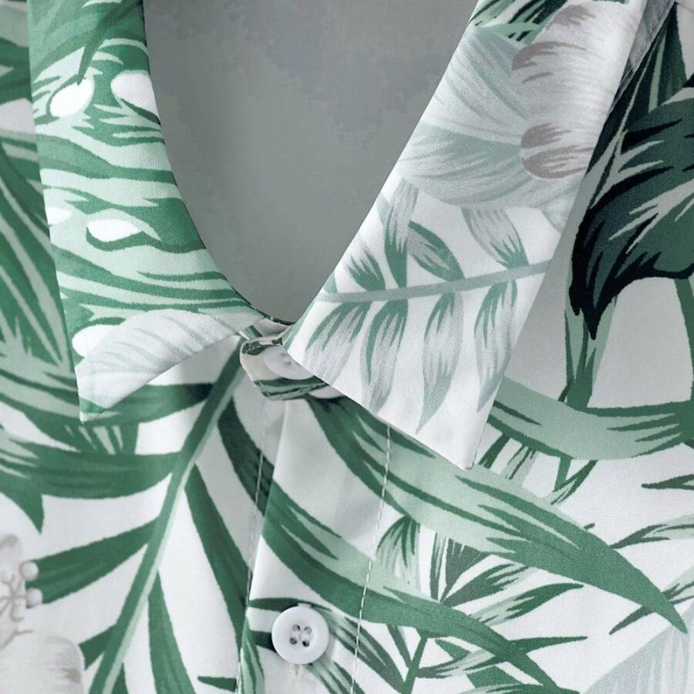 Detalhe da gola da camisa masculina Vinser Comporta branca com estampa de folhagens verdes e fechamento frontal com botão.