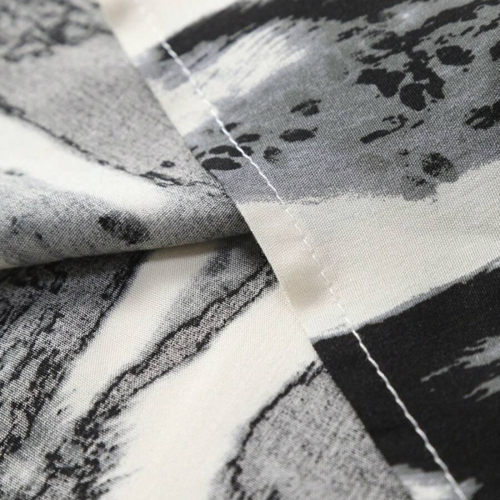 Detalhe da costura da Camisa Vinser Costa Noturna, evidenciando o acabamento reforçado e a estampa abstrata em preto, branco e cinza sobre tecido leve e macio.