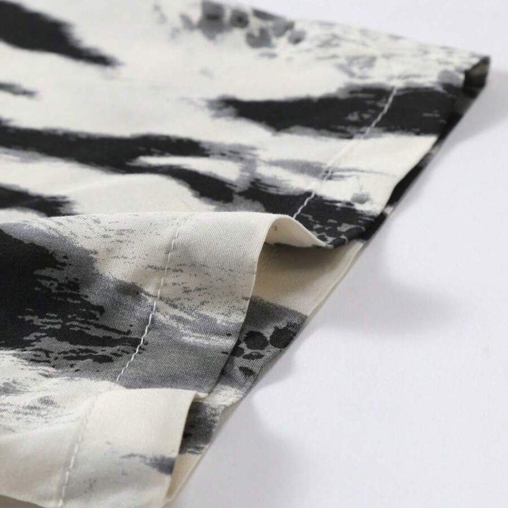 Detalhe da manga da Camisa Vinser Costa Noturna, destacando a barra com acabamento reforçado e a estampa abstrata em preto, branco e cinza sobre tecido leve.