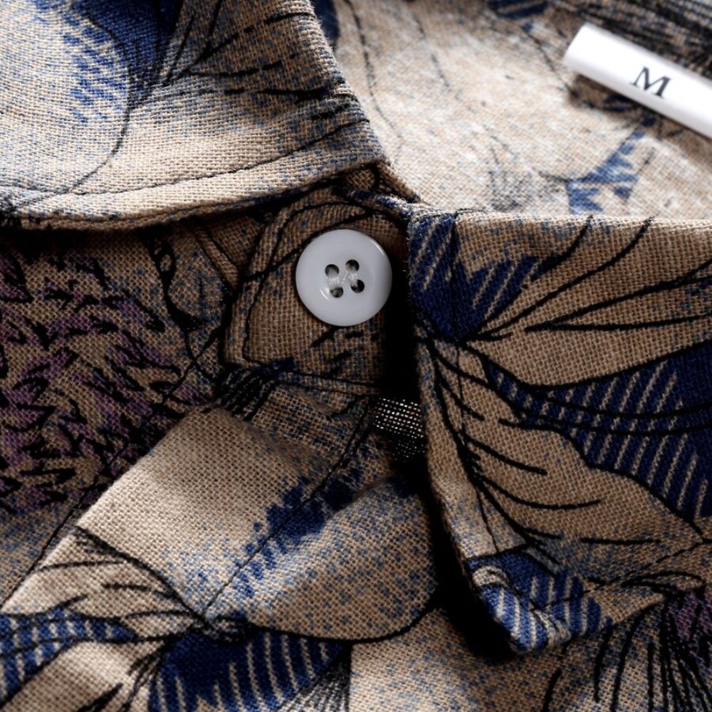 Detalhe da gola da Camisa Vinser Costa Serena com acabamento refinado, botão frontal e estampa floral em tons de bege, marrom e azul.