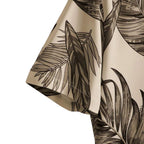 Detalhe da manga da Camisa Vinser Duna Atlântica, com estampa tropical de folhas em tons de marrom sobre fundo bege, evidenciando o acabamento da costura e a leveza do tecido.