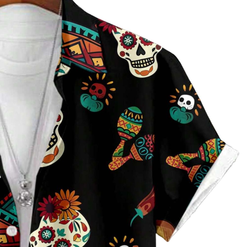 Detalhe da manga da Camisa Vinser Fiesta, destacando o acabamento dobrado, as costuras reforçadas e a estampa temática mexicana com caveiras, violões, sombreros e flores coloridas sobre fundo preto, evidenciando a leveza do tecido e a qualidade dos acabamentos.