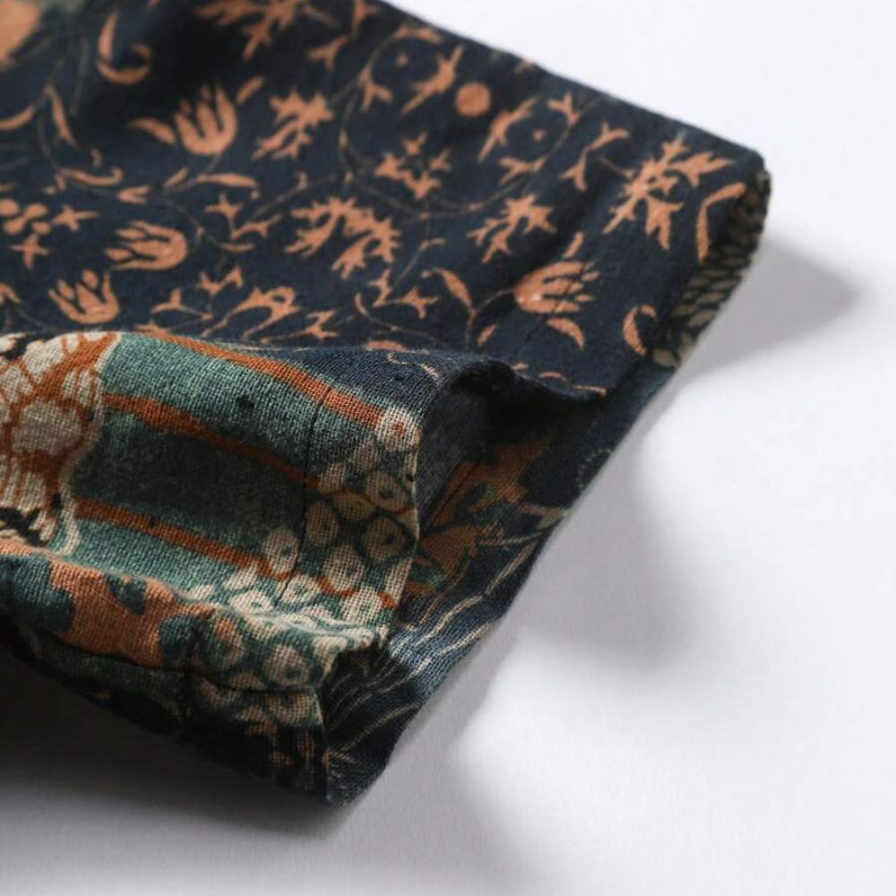 Detalhe da manga da camisa masculina Vinser Guajiru com estampa floral e geométrica em tons de azul, bege e terracota.