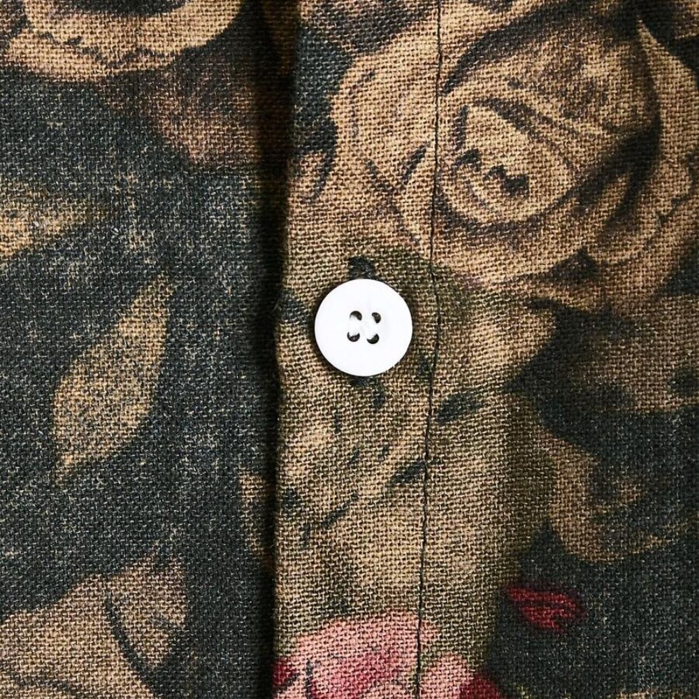 Close do botão frontal da Camisa Vinser Jardim Noturno, destacando o tecido texturizado, o acabamento premium e a estampa floral em tons terrosos sobre fundo escuro.