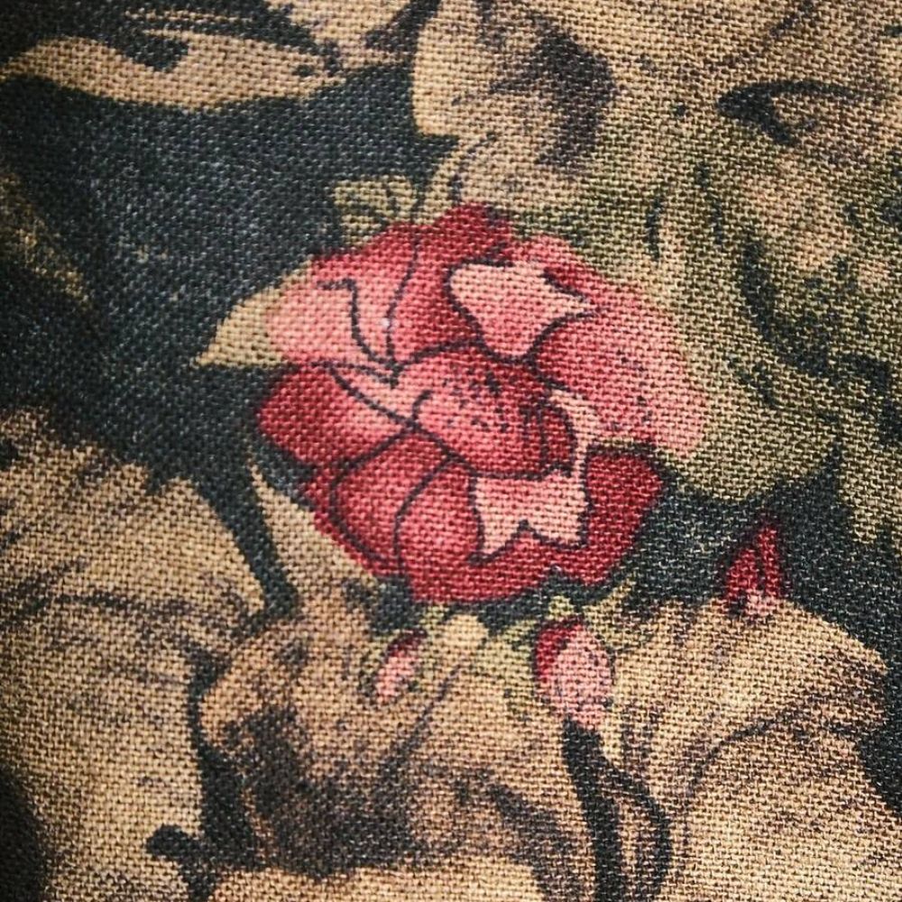 Close do tecido da Camisa Vinser Jardim Noturno, destacando a textura encorpada, a estampa floral em tons terrosos com detalhe em vermelho e o acabamento premium.