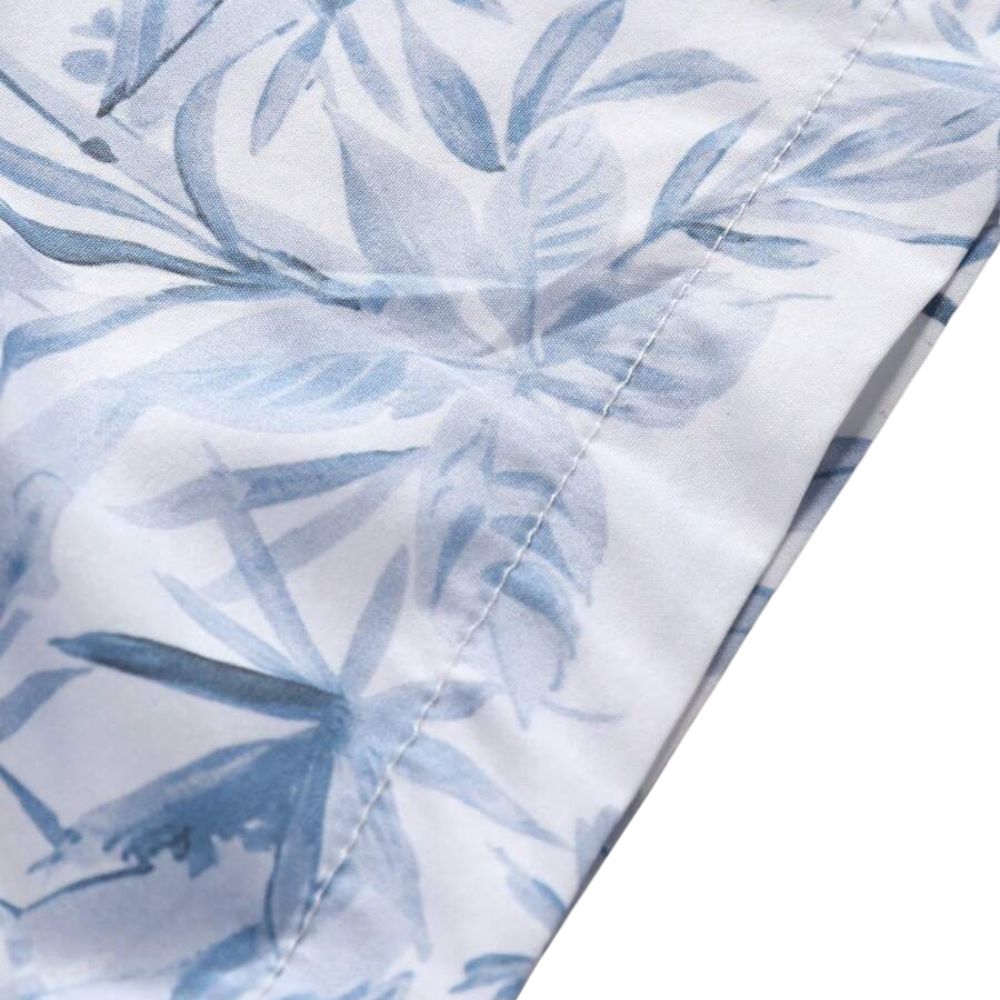 Detalhe da manga da Camisa Vinser Maragogi, destacando o acabamento dobrado, as costuras reforçadas, a estampa tropical em tons de azul e o tecido leve e respirável, evidenciando a qualidade premium da peça.