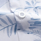Detalhe do tecido da Camisa Vinser Maragogi, destacando a estampa tropical em tons de azul, o botão branco, as costuras reforçadas e o tecido leve e respirável, evidenciando o acabamento premium da peça