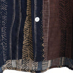 Detalhe do botão da Camisa Vinser Marrakesh, destacando as costuras reforçadas, o acabamento refinado e a estampa listrada étnica em tons de marrom, azul-marinho, bege e preto, evidenciando a qualidade do tecido e dos acabamentos.