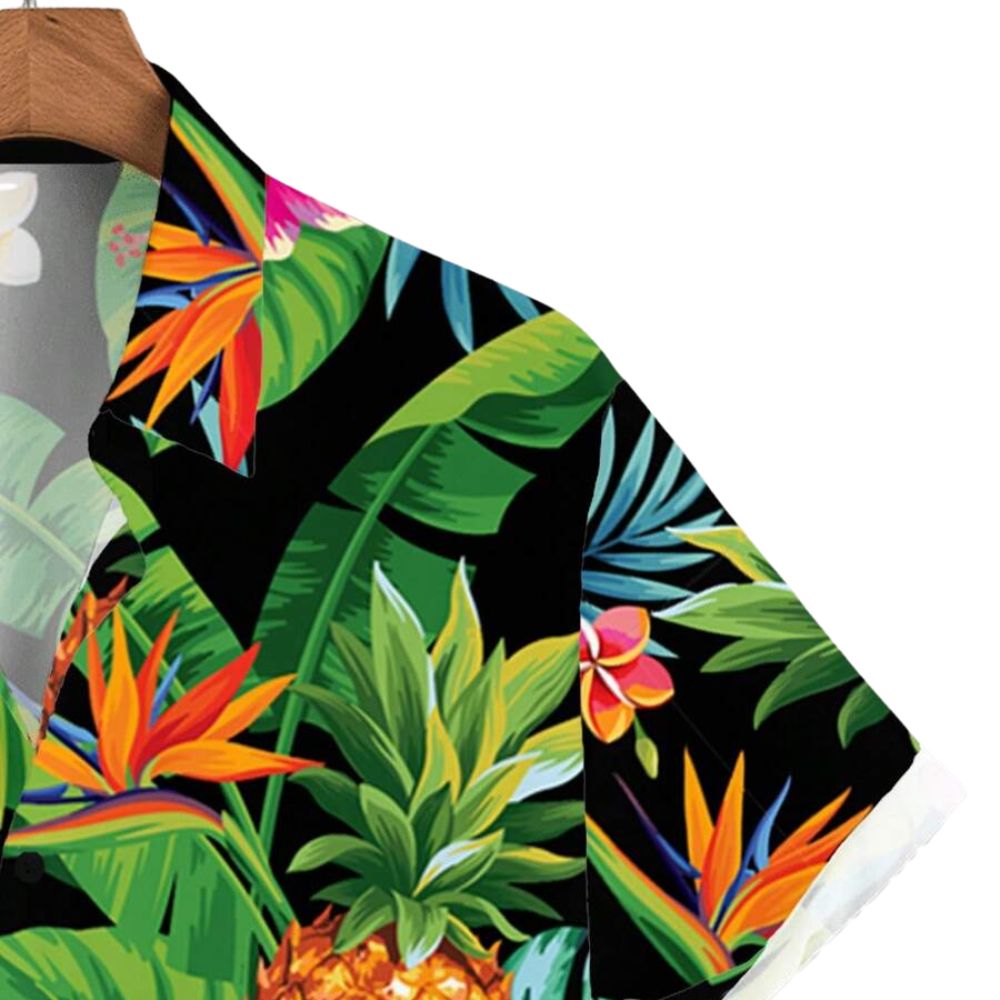 Detalhe da manga da Camisa Vinser Maui com estampa tropical em fundo preto, destacando folhas, flores e abacaxis coloridos, além do acabamento refinado, das costuras reforçadas e do tecido leve e respirável.