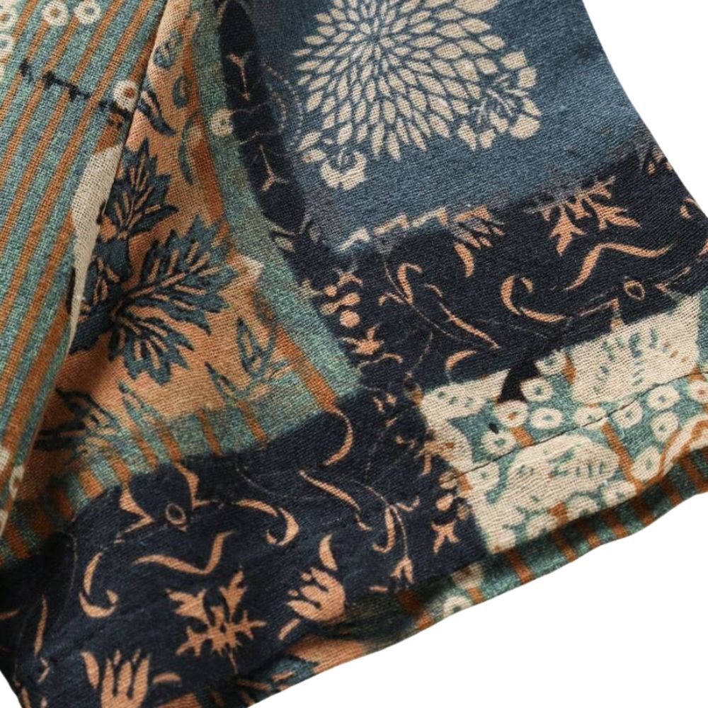 Detalhe da manga da Camisa Vinser Mosaico, destacando o acabamento dobrado, as costuras reforçadas e a estampa patchwork em tons de verde-musgo, bege, marrom e preto, evidenciando a qualidade do tecido e dos acabamentos.