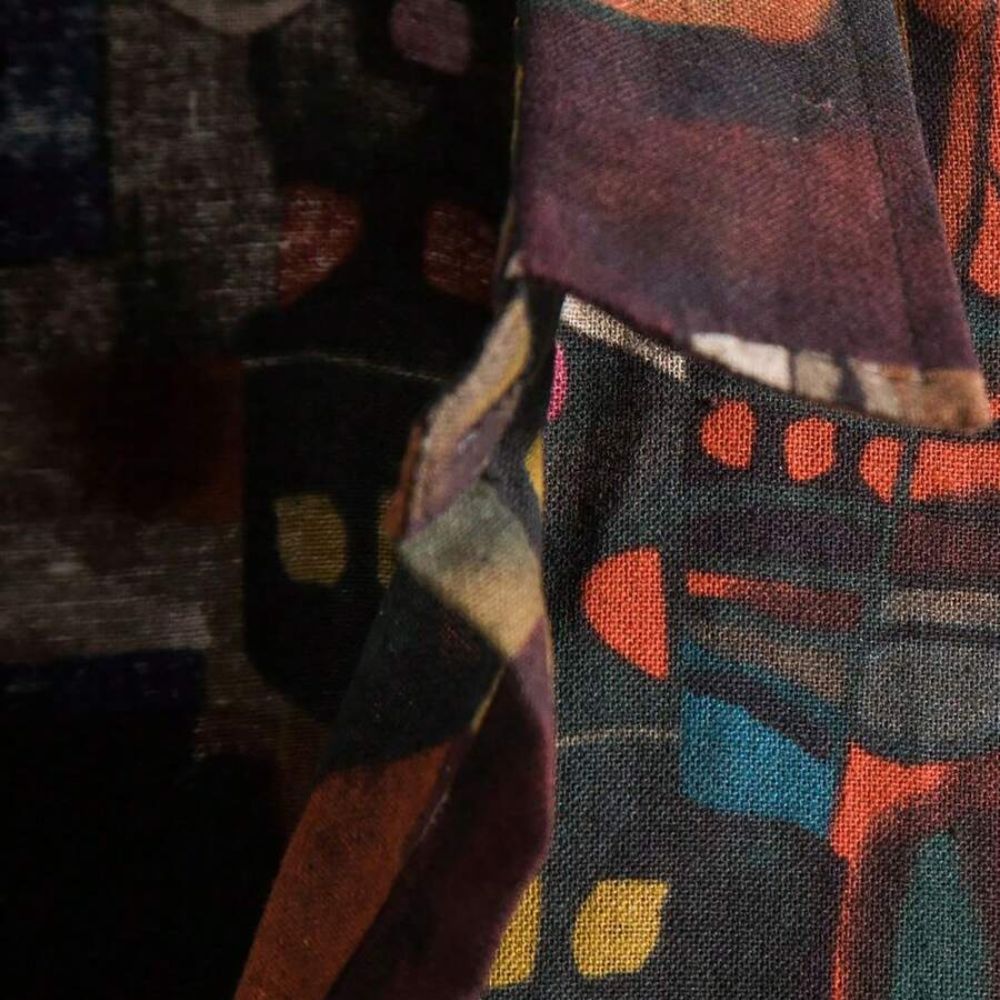 Detalhe da estampa geométrica abstrata da camisa masculina Vinser Niterói em tons escuros, terrosos e azul.