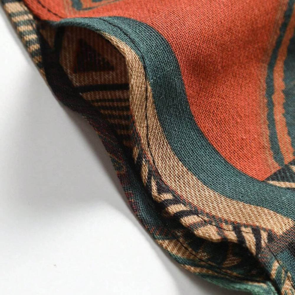 Detalhe da Camisa Vinser Nomad destacando as costuras reforçadas, o acabamento refinado e a estampa patchwork geométrica em tons de verde, terracota, bege e marrom, evidenciando a textura e a qualidade do tecido.