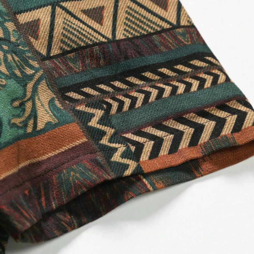 Detalhe da manga da Camisa Vinser Nomad, destacando o acabamento dobrado, as costuras reforçadas e a estampa patchwork geométrica em tons de verde, terracota, bege e marrom, evidenciando a qualidade do tecido e dos acabamentos.