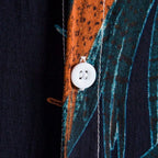 Detalhe do botão da Camisa Vinser Noronha, destacando os botões frontais, as costuras reforçadas, o acabamento refinado e a estampa tropical de folhas em tons de laranja e azul-petróleo sobre fundo azul-marinho, evidenciando a qualidade premium da peça.