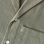 Detalhe do tecido da Camisa Vinser Oliva, destacando a textura suave, o acabamento refinado e o tecido leve na cor verde oliva, ideal para conforto e elegância no dia a dia.