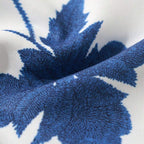 Close do tecido da camisa masculina Vinser Pajuçara, destacando a textura premium e a estampa floral azul sobre fundo branco.