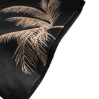Detalhe da manga da camisa masculina Vinser Palm Noir, com estampa de palmeiras em tons terrosos sobre fundo preto, evidenciando o acabamento da costura e a qualidade do tecido.