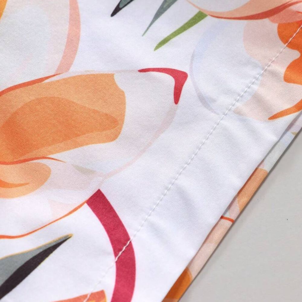 Close da manga da Camisa Vinser Porto do Sol, destacando o acabamento da costura, o tecido leve e a estampa tropical em tons de laranja, verde e branco.