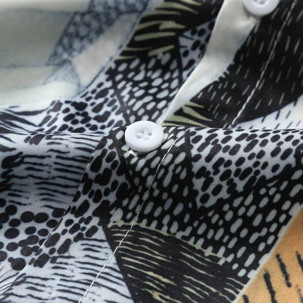 Close do tecido da Camisa Vinser Riviera Geo, destacando a estampa geométrica em preto, branco, cinza e bege, além do acabamento dos botões e da textura do tecido.