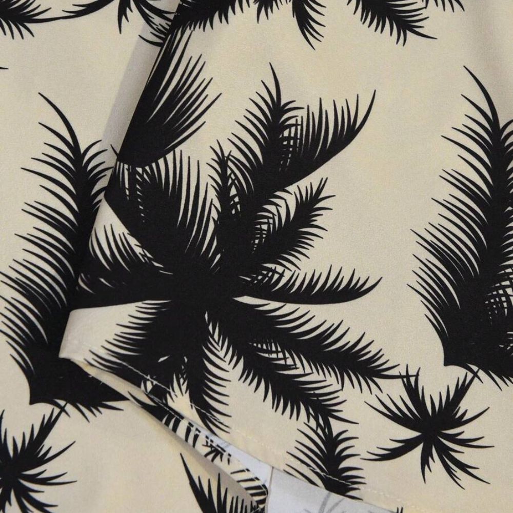 Detalhe da estampa tropical preta de folhas e palmeiras da Camisa Vinser Saint-Tropez em fundo bege