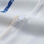 Detalhe do botão da Camisa Vinser Santorini, destacando os botões frontais, as costuras reforçadas, o acabamento refinado e a estampa listrada em azul e bege sobre fundo branco, evidenciando a qualidade premium da peça.
