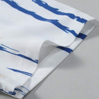 Detalhe da manga da Camisa Vinser Santorini, destacando o acabamento dobrado, as costuras reforçadas e a estampa listrada em azul e bege sobre fundo branco, evidenciando a leveza do tecido e a qualidade dos acabamentos.