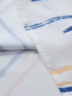 Detalhe do tecido da Camisa Vinser Santorini, destacando a estampa listrada em azul e bege sobre fundo branco, a textura suave do tecido, o acabamento refinado e a qualidade premium, proporcionando conforto, leveza e elegância.