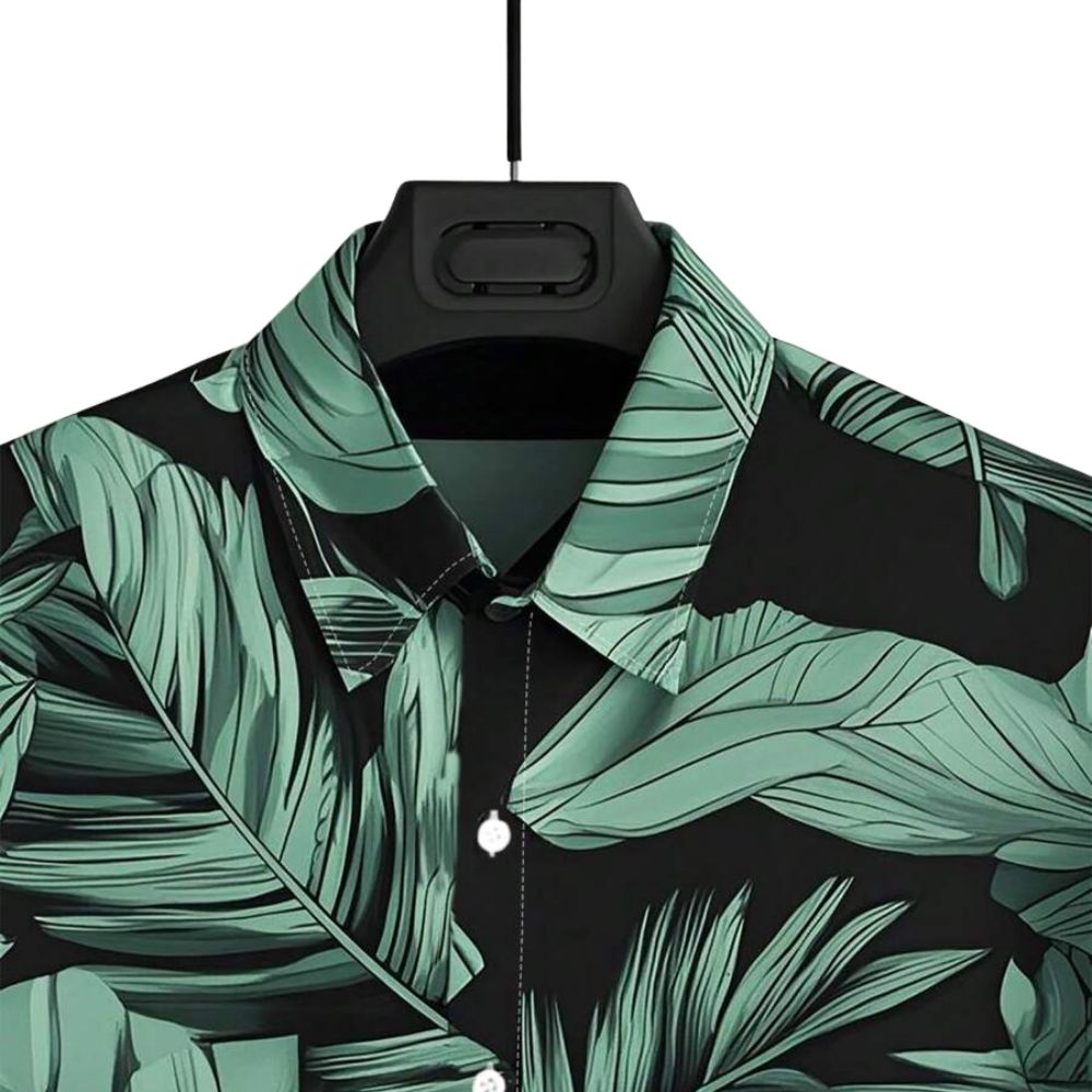 Detalhe da gola da Camisa Vinser Selva Costeira, destacando o acabamento refinado, a estampa tropical de folhas verdes e o tecido de toque leve.