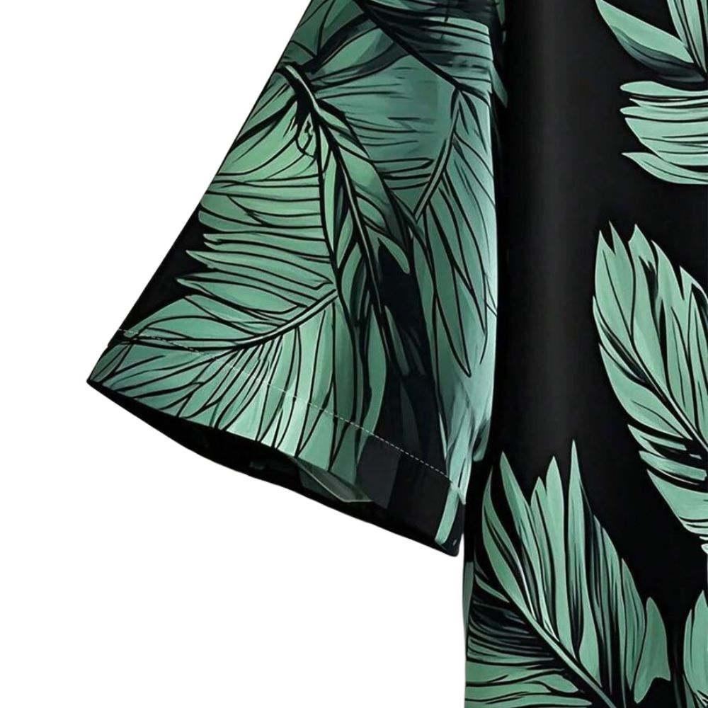 Detalhe da manga da Camisa Vinser Selva Costeira, destacando o acabamento da costura, a modelagem e a estampa tropical de folhas verdes sobre fundo preto.