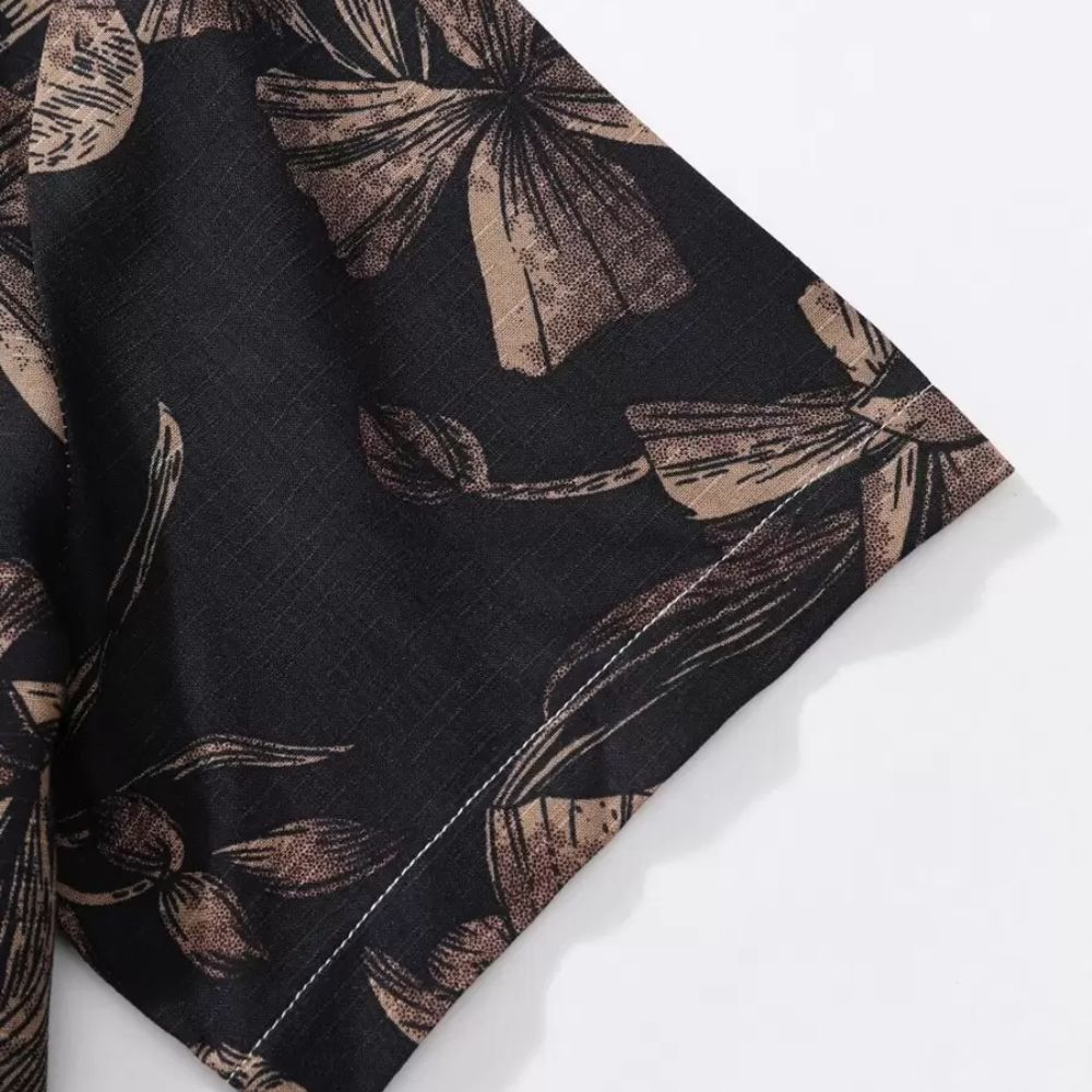 Close da manga da Camisa Vinser Selva Noturna, destacando a estampa floral em tons de marrom sobre fundo preto, o tecido leve, o acabamento da manga curta e a qualidade da confecção.