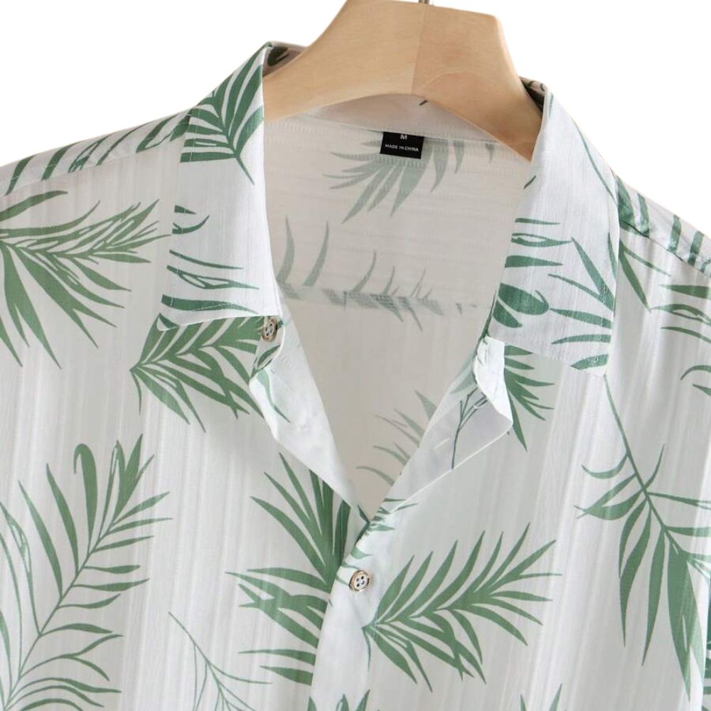 Detalhe da Camisa Vinser Seychelles branca com gola aberta, botões e estampa de folhas verdes