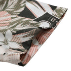 Detalhe da manga da Camisa Vinser Sunset Bloom, destacando o acabamento da barra e a estampa tropical com folhas e flores em tons de rosa, branco e verde sobre fundo escuro.