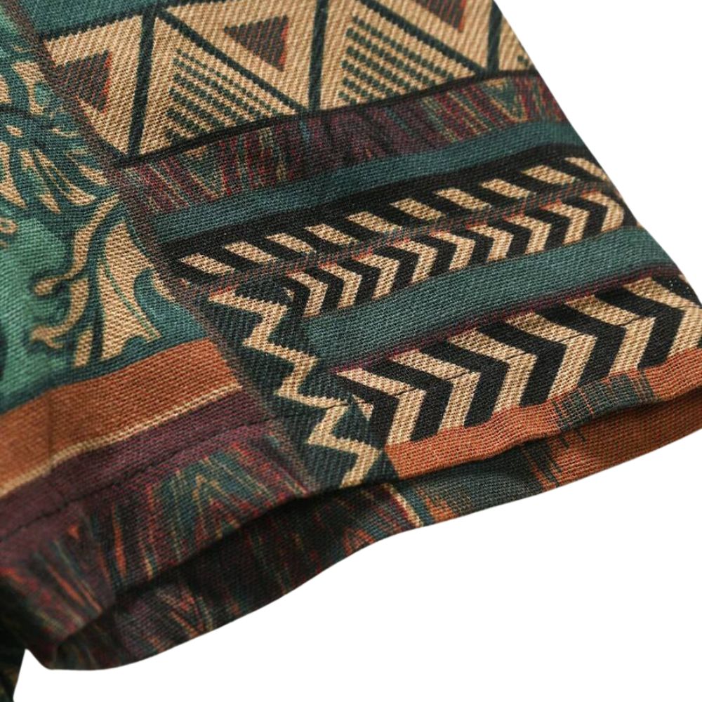 Detalhe da manga da Camisa Vinser Terral, destacando o acabamento dobrado, as costuras reforçadas e a estampa patchwork em tons de terracota, verde-musgo, bege e marrom, evidenciando a leveza do tecido e a qualidade dos acabamentos.